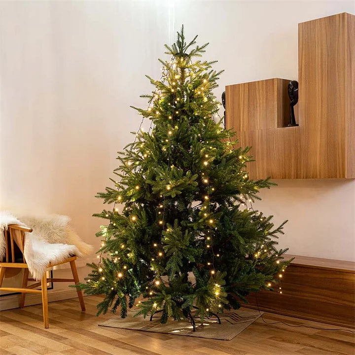 Decorated Christmas tree with lights in a room with wooden furniture.