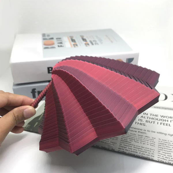 Stack of pink textured cards held by a hand with a magazine in the background