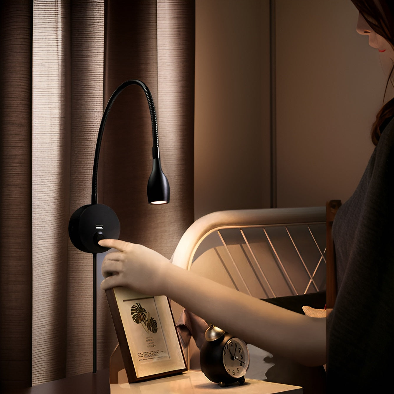 Person adjusting a flexible neck lamp on a table with a curtain in the background