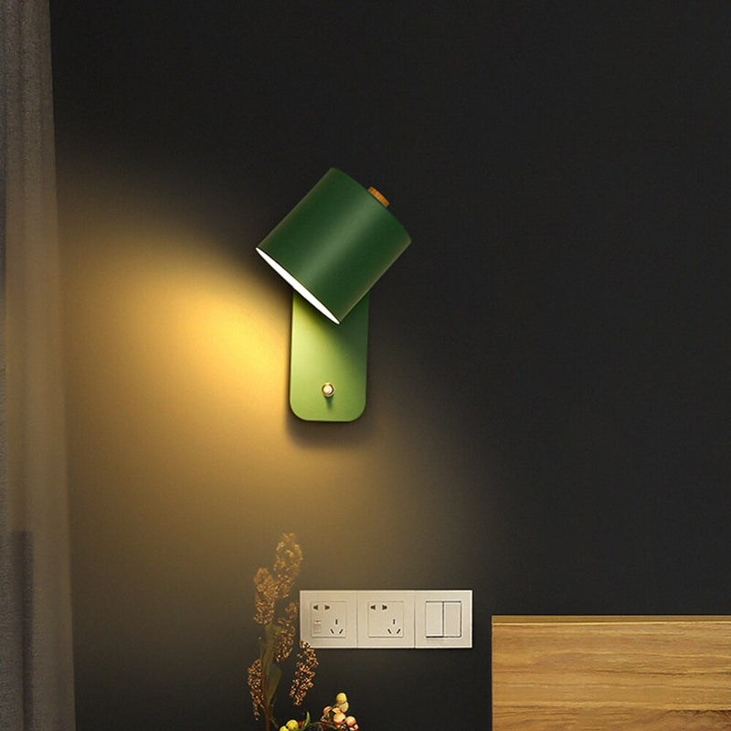 Green wall lamp on a dark wall with a wooden baseboard.