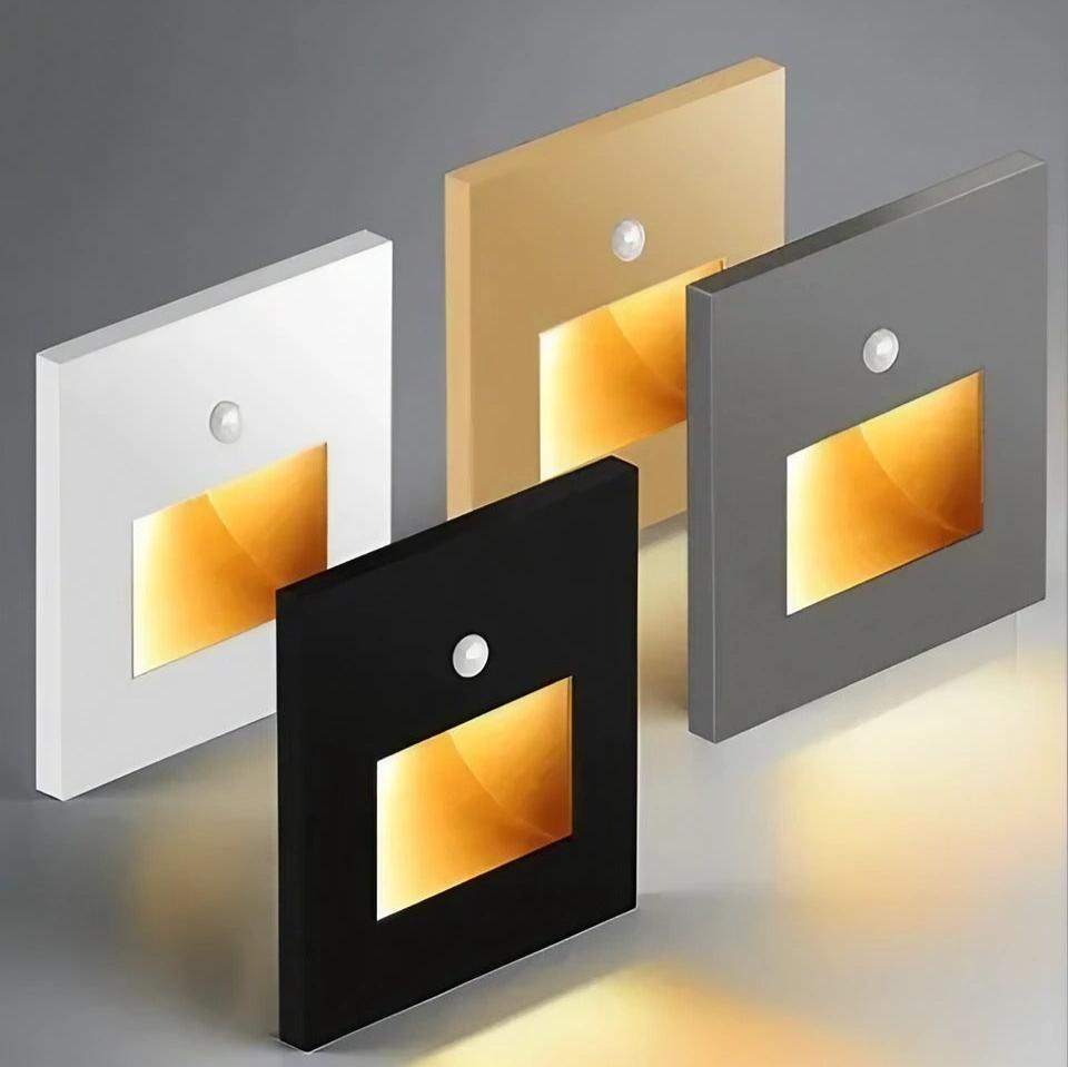 Four square wall lights in white, gold, black, and gray on a gray background.