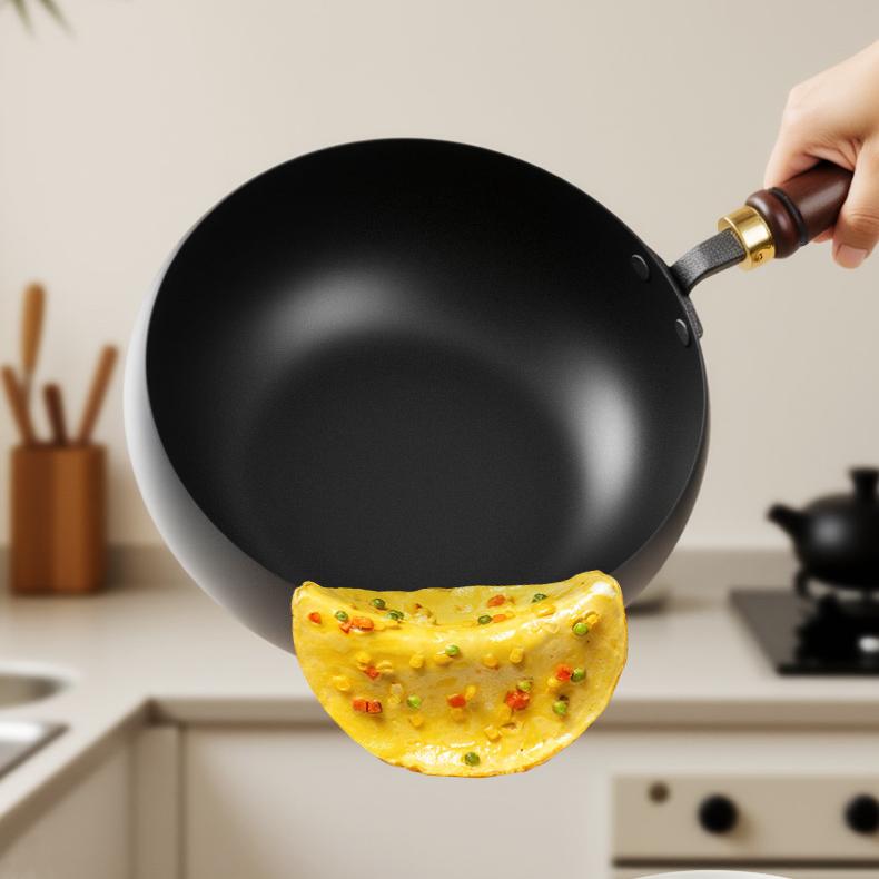 Person holding a black wok with a cooked omelette in a kitchen setting