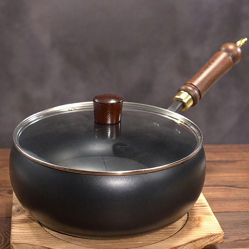 Black frying pan with wooden handle on a wooden surface