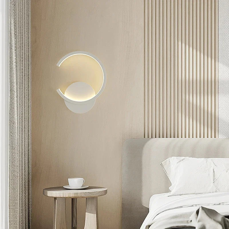 Modern wall light fixture in a bedroom setting with a bed and side table.