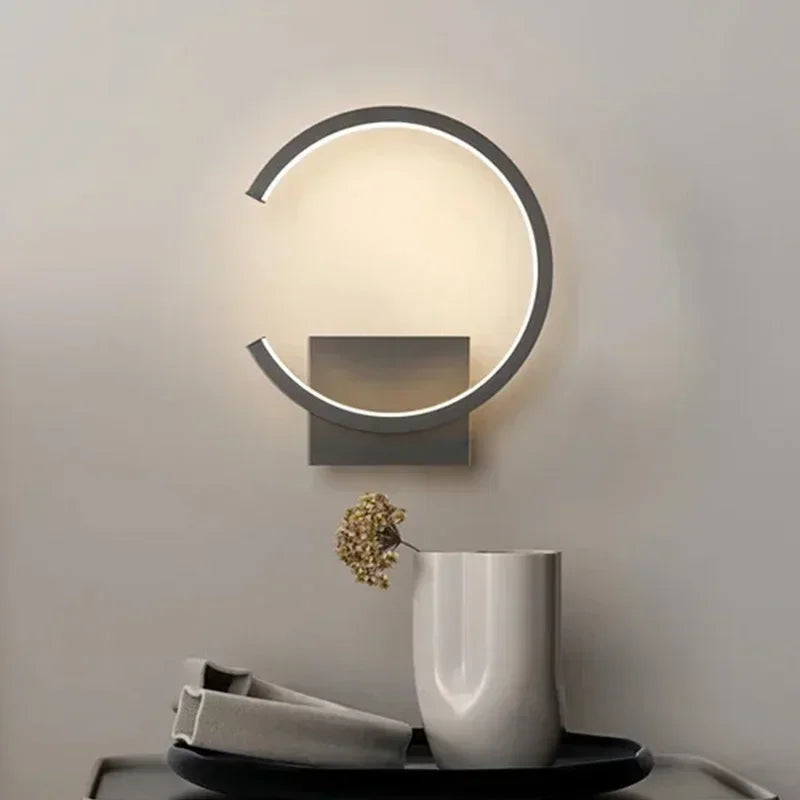 Modern wall lamp with a decorative vase and plant on a table below.