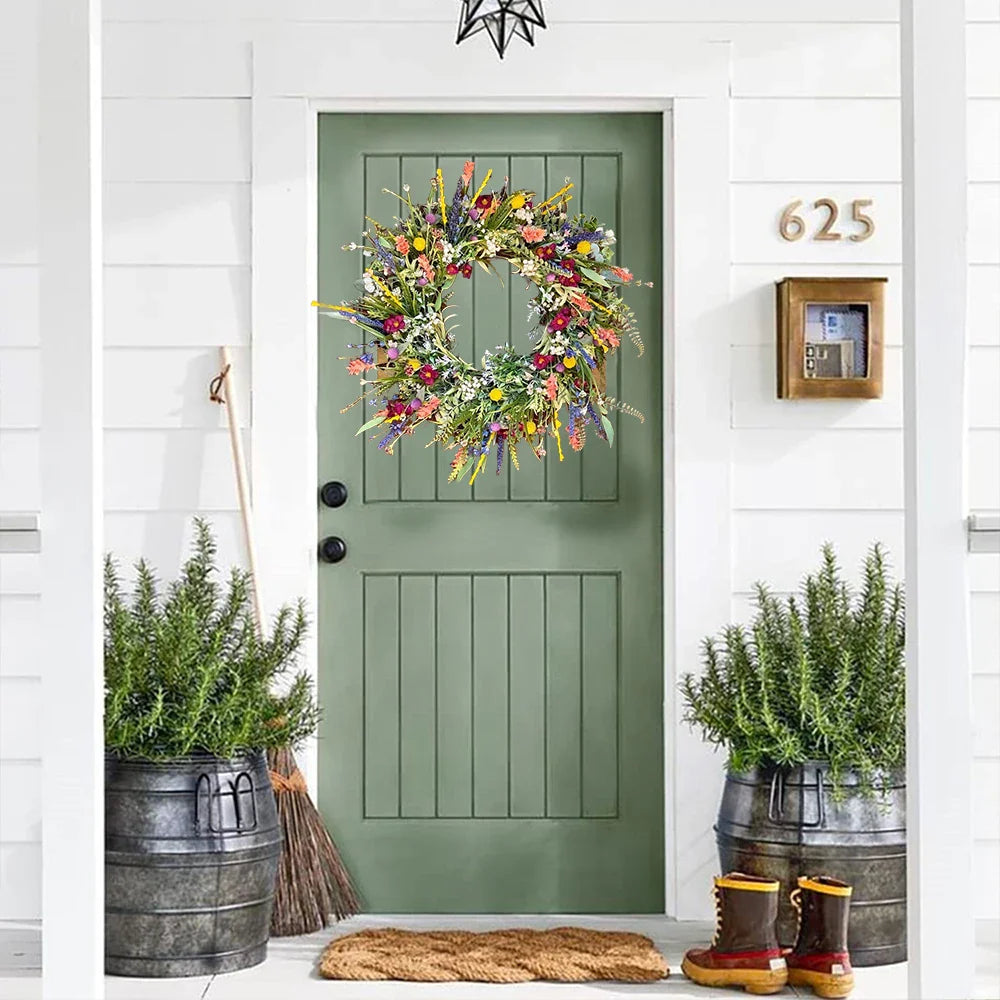 Green front door with floral wreath, potted plants, and boots on a white wall.