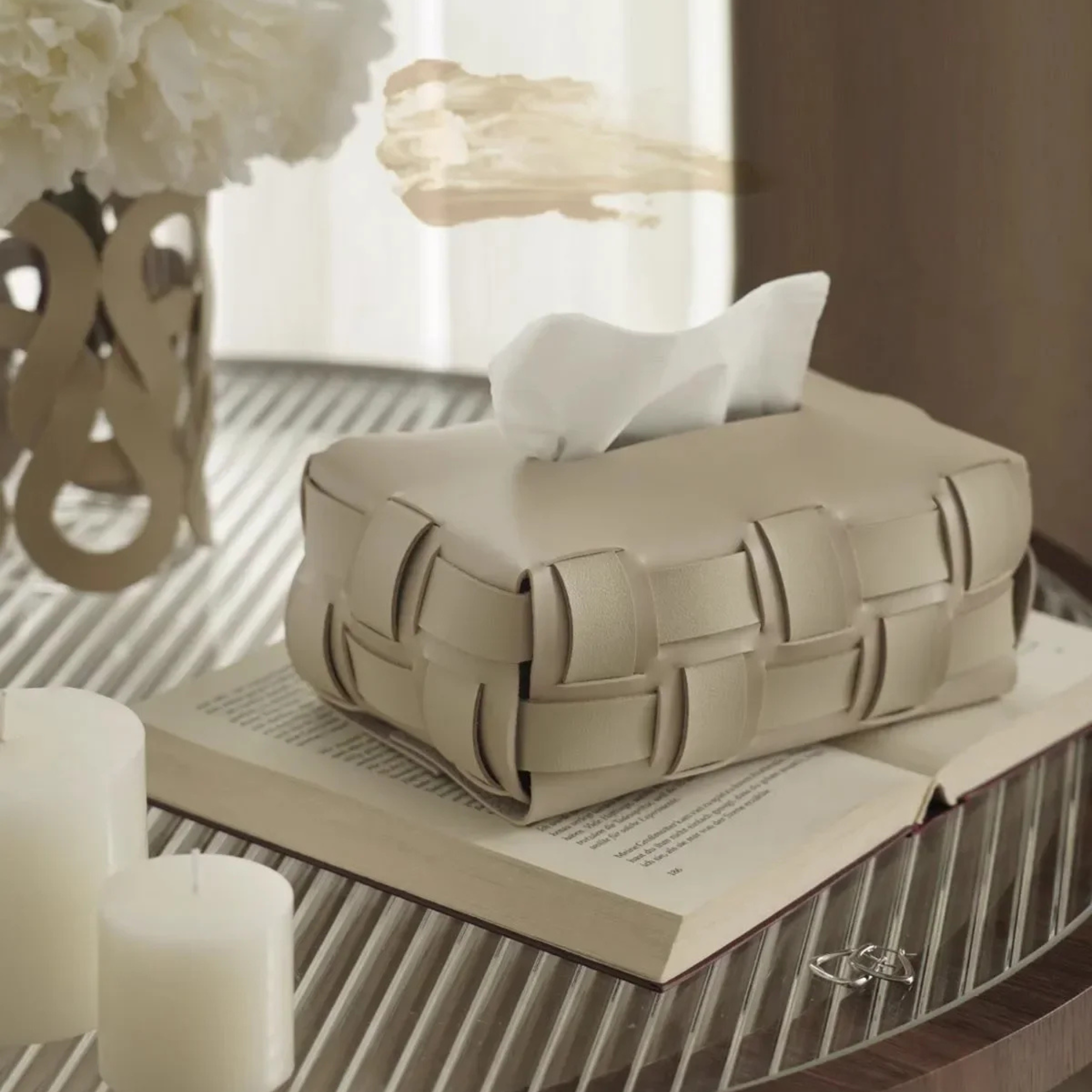Beige woven tissue box on an open book with a blurred background