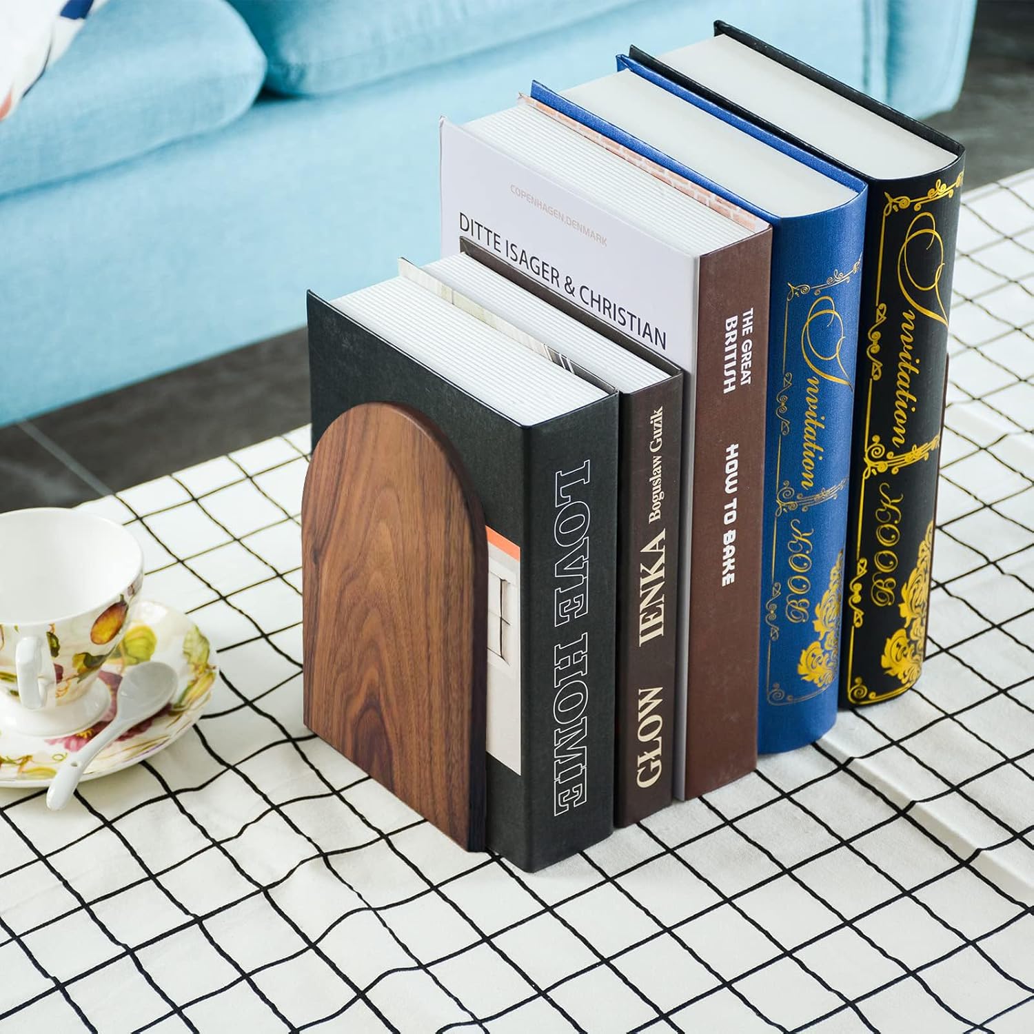 Stack of books on a checkered tablecloth with a light blue couch in the background