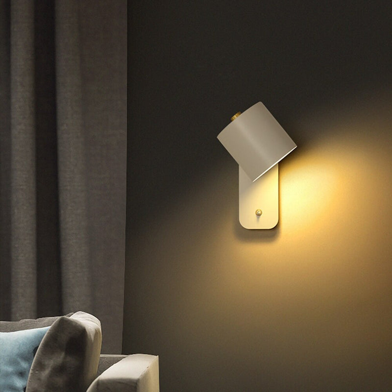 Modern wall lamp on a dark wall with a soft glow, next to a gray sofa.