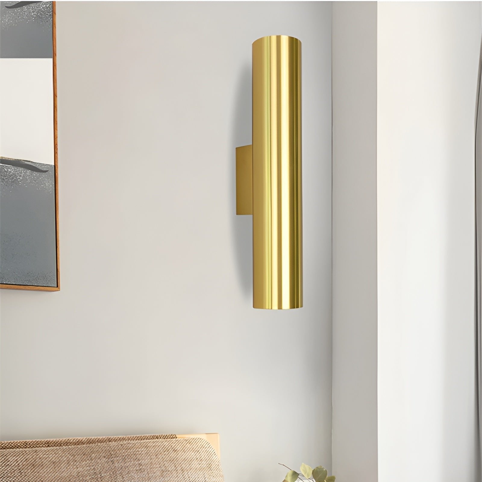 Gold wall sconce on a white wall with a minimal background