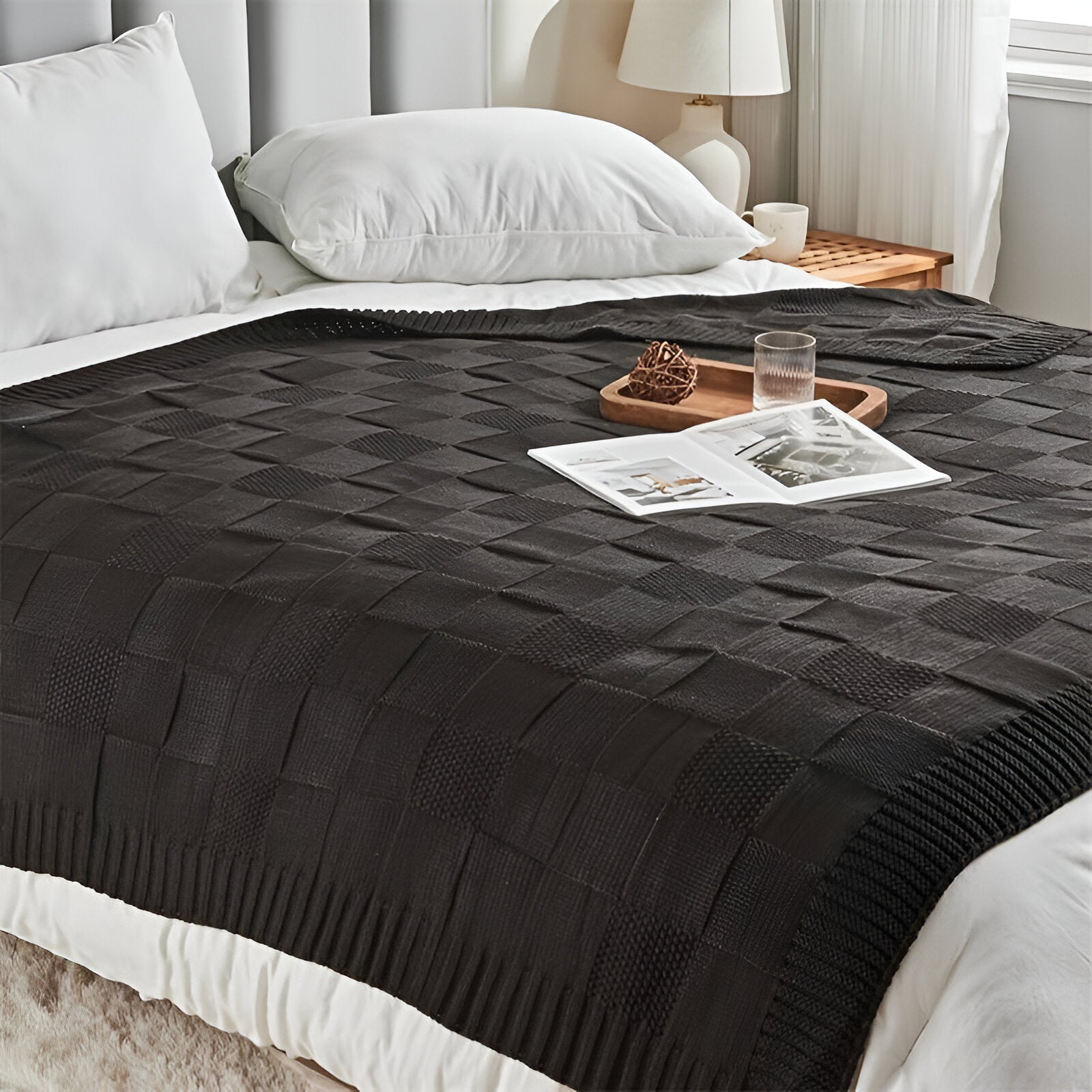 Black textured blanket on a bed with a tray and glasses in a bedroom setting