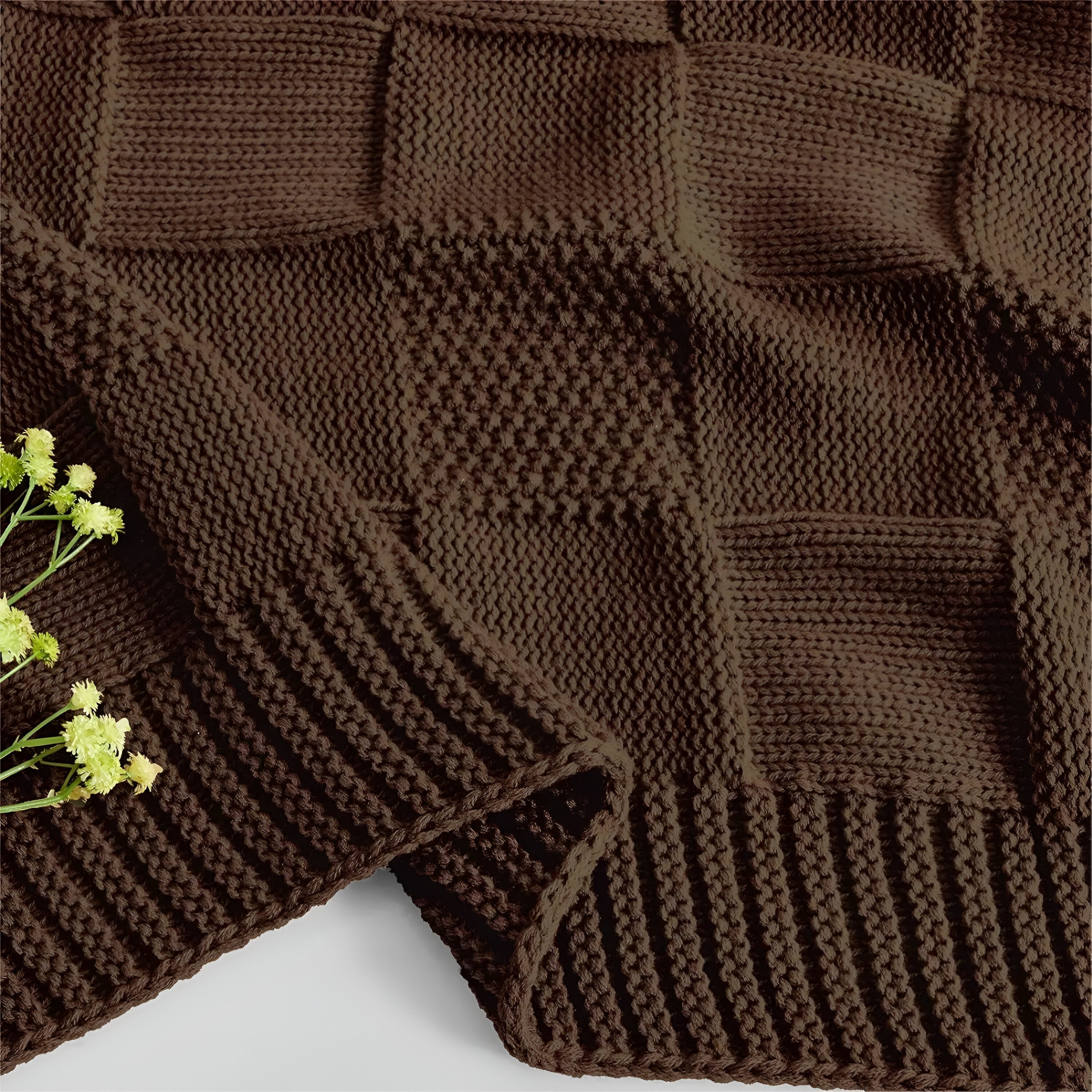 Brown knitted blanket with a floral arrangement on a light background