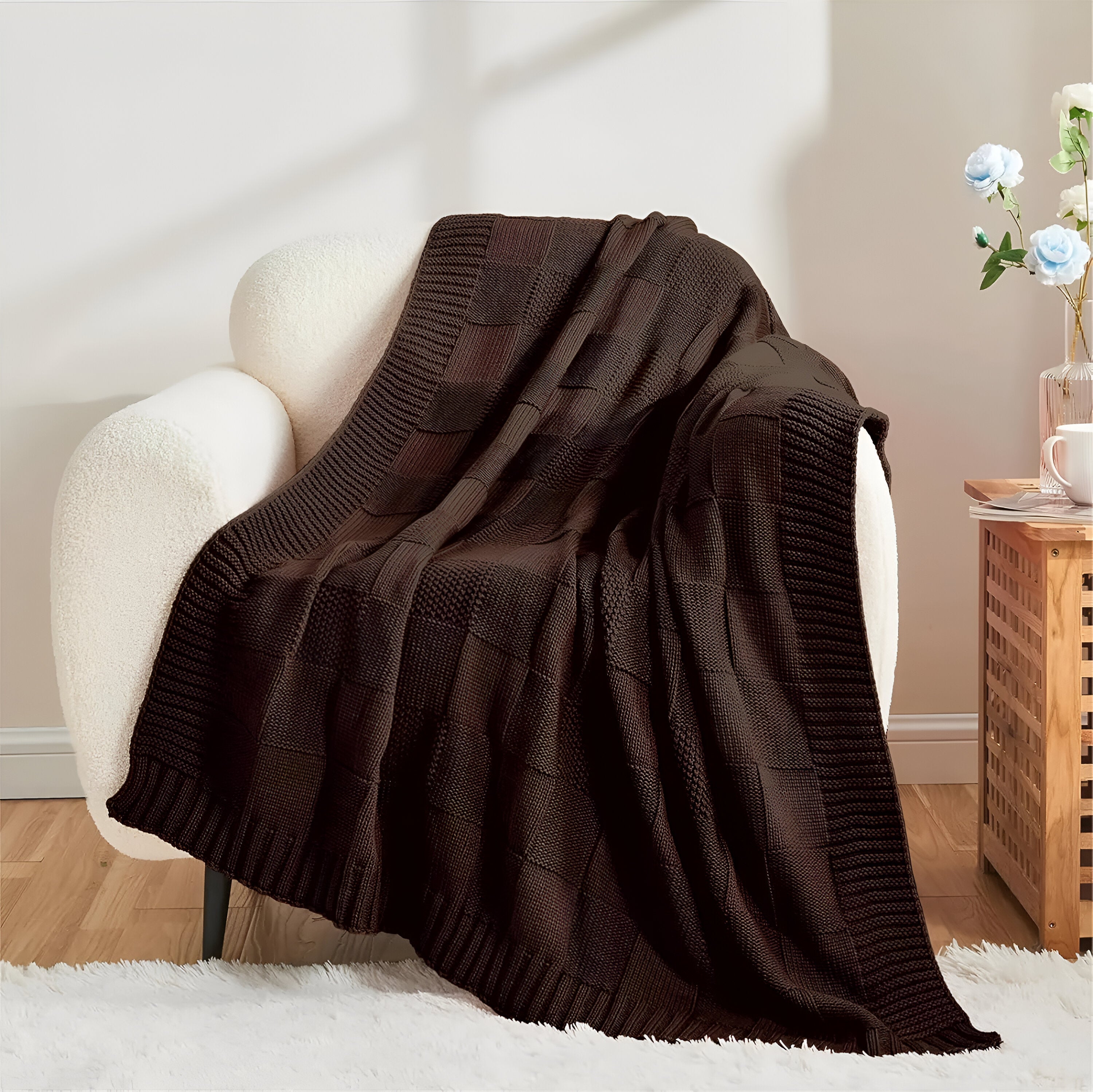 Brown knitted blanket draped over a white armchair in a cozy room.