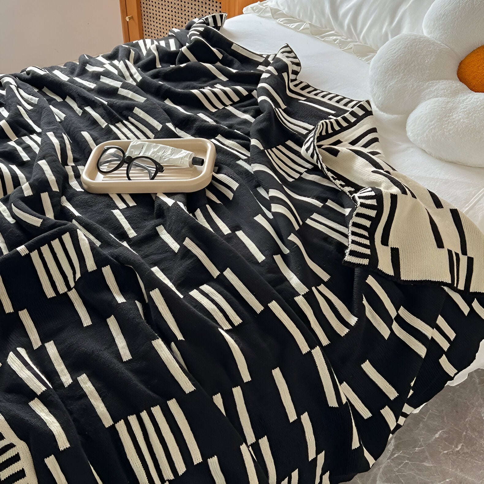 Black and white patterned blanket draped over a bed with a tray and glasses on top.