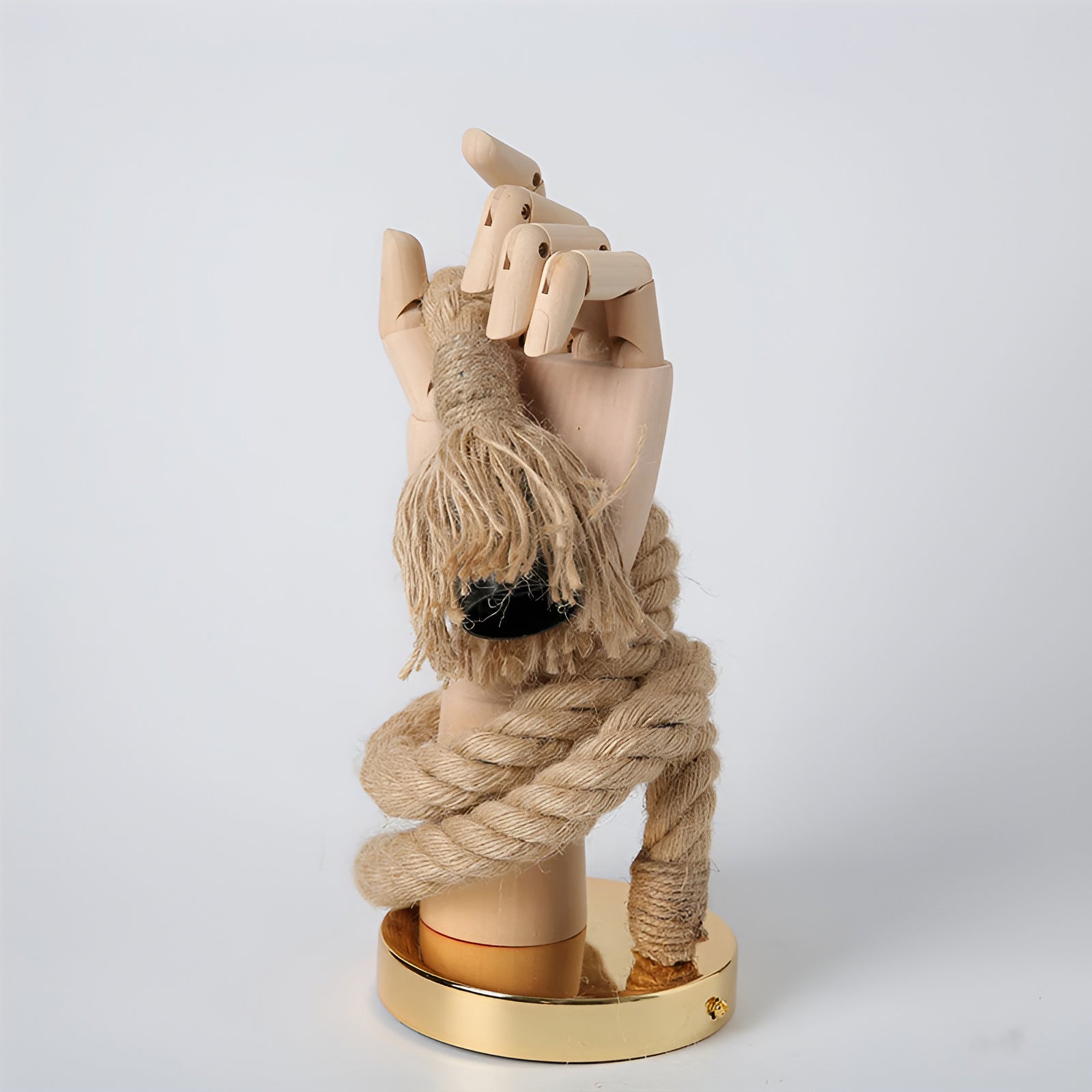 Wooden figure with rope and gold base on a light gray background