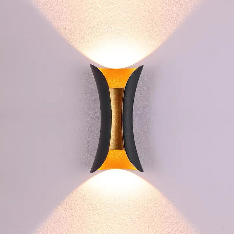 Modern wall lamp with black and gold design on a light gray wall.