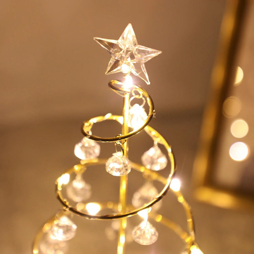 Decorative gold Christmas tree with star topper on a reflective surface