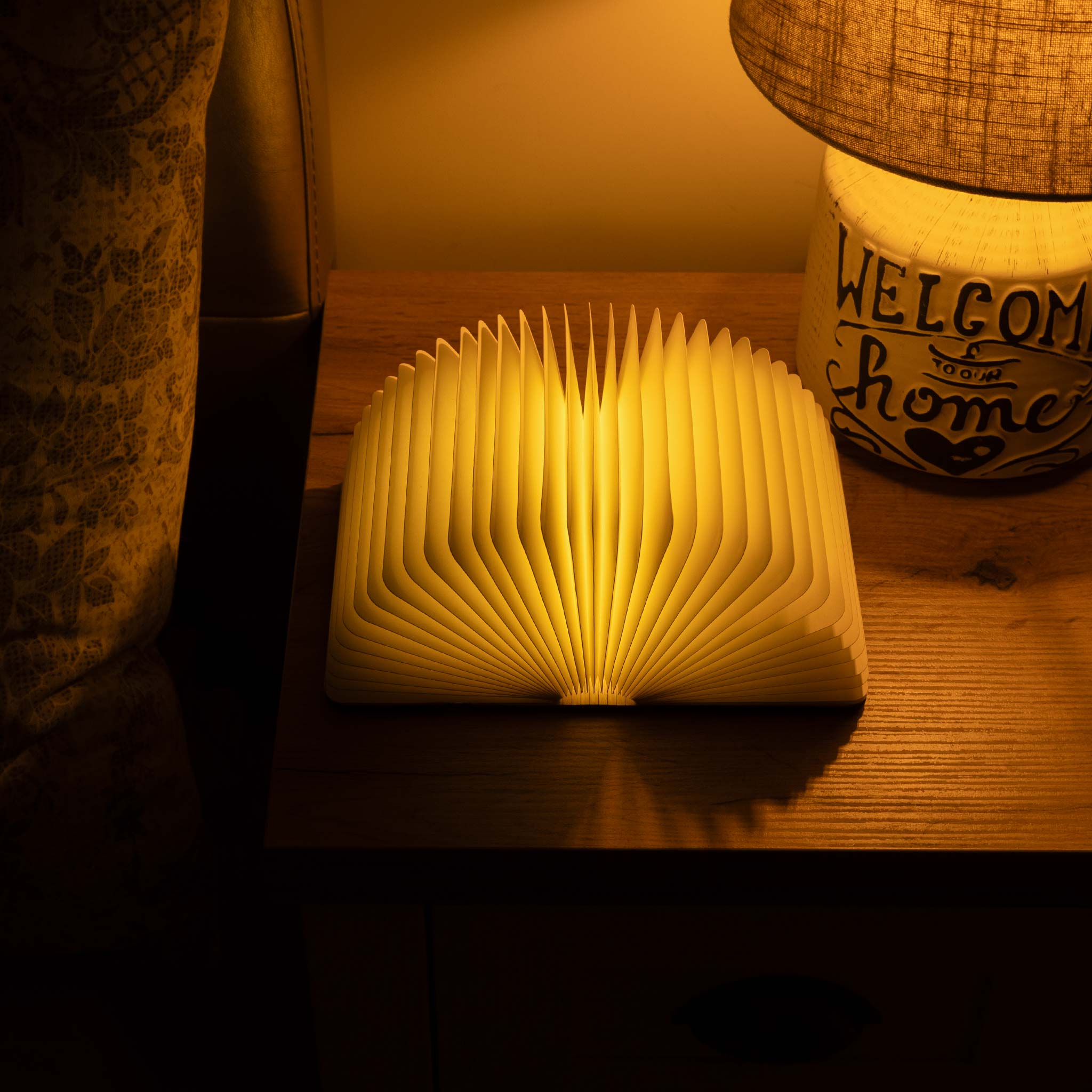 Wooden book-shaped lamp emitting a warm glow on a wooden surface.