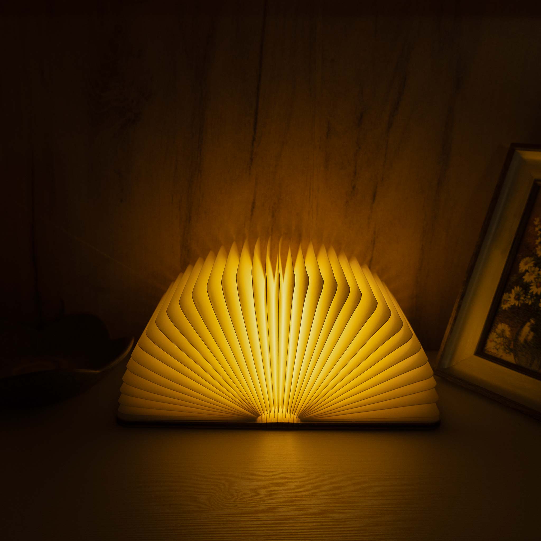 Book-shaped lamp emitting a warm glow on a dark surface.