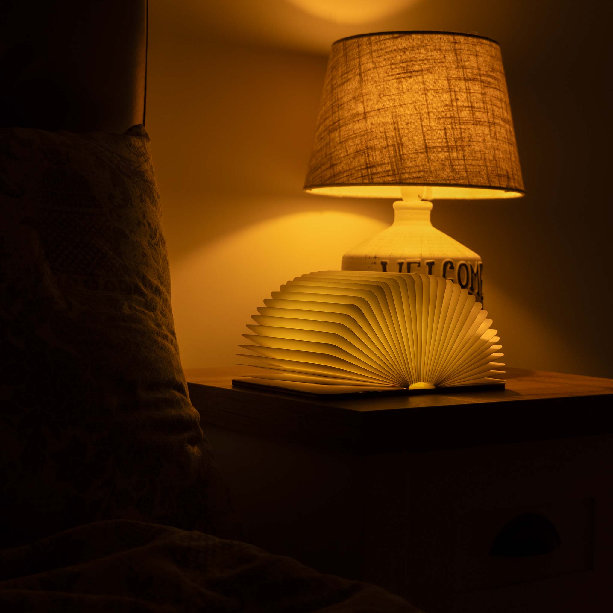 Book-shaped lamp with a textured shade on a dark background