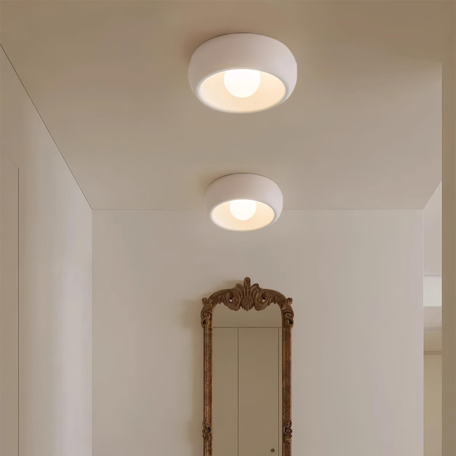 Two ceiling lights in a room with a tall mirror on the wall.
