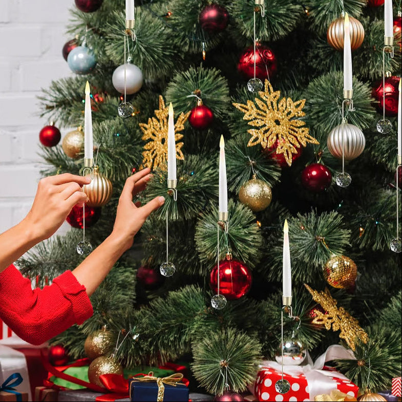 Person decorating a Christmas tree with ornaments and candles