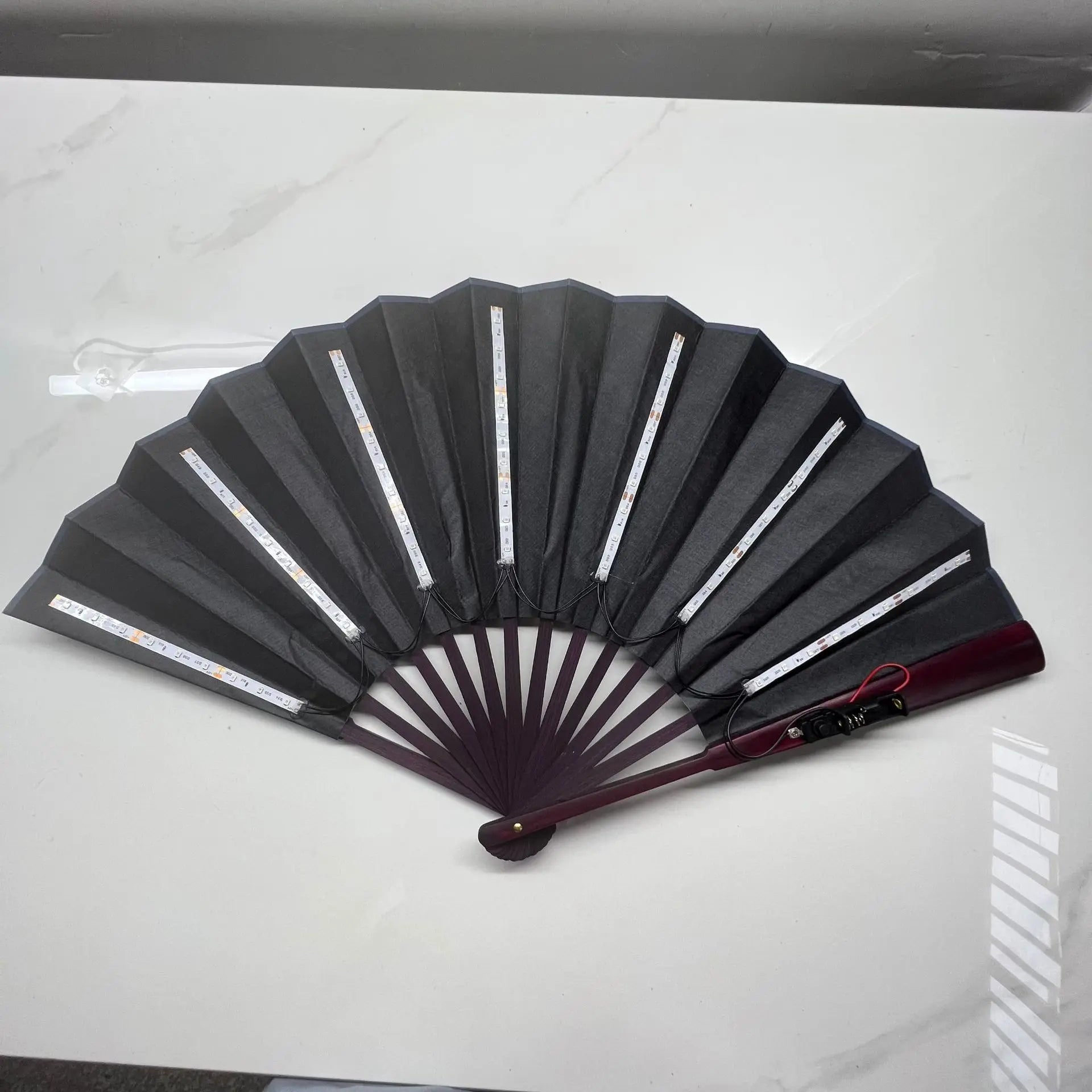 Black folding fan with red handle on a white background