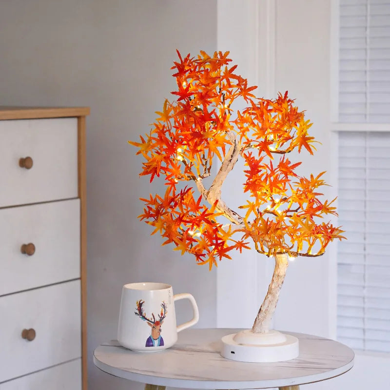 Decorative tree lamp with orange leaves on a small round table next to a mug with a deer design.