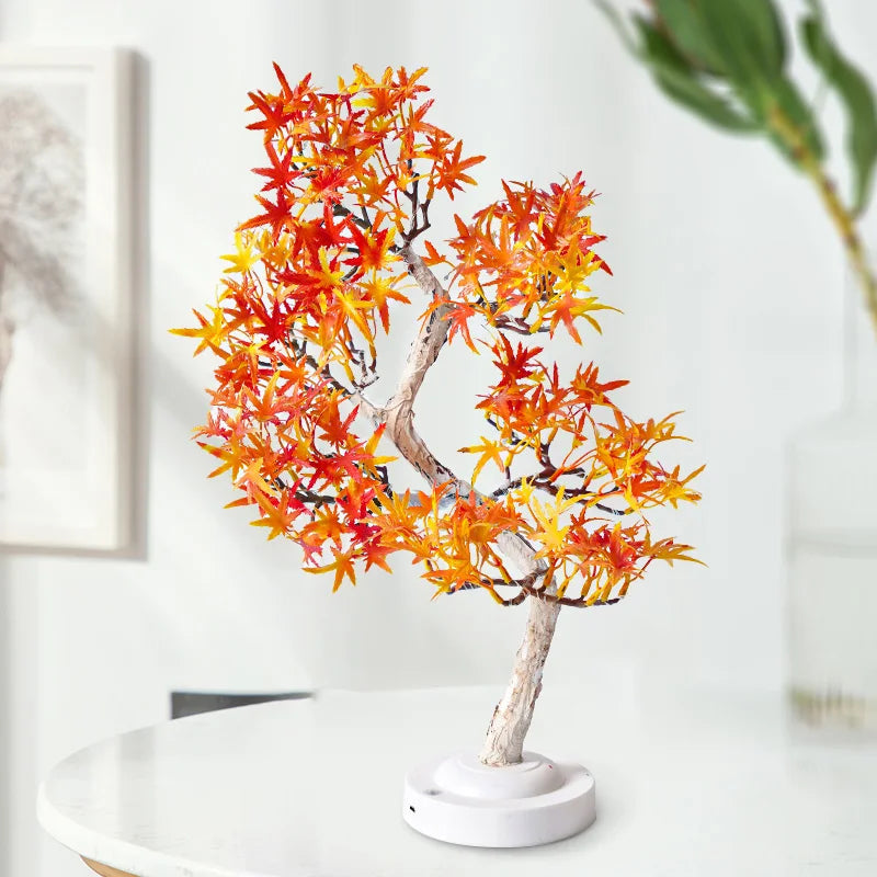 Small decorative tree with autumn-colored leaves on a white surface