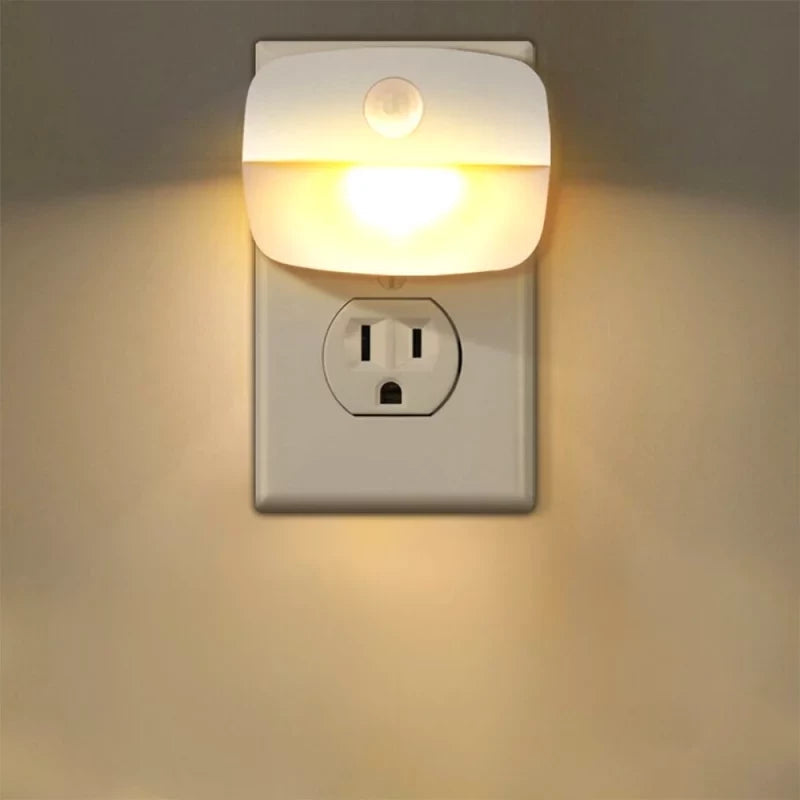 Plug-in night light emitting a warm glow on a wall socket.