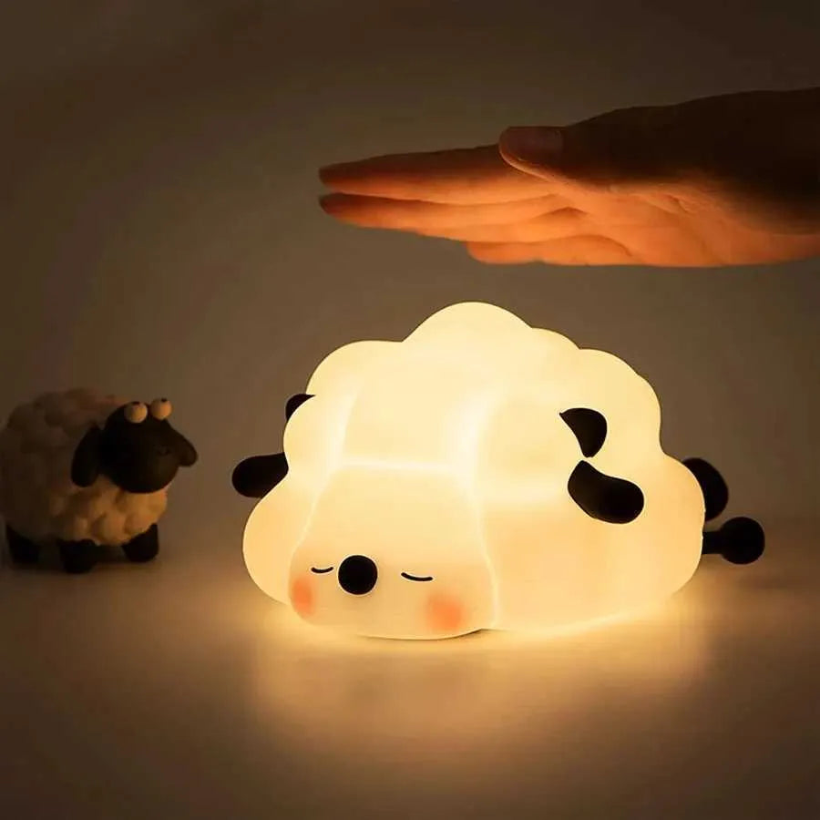 Sheep-shaped night light glowing with a hand reaching out to it on a plain background