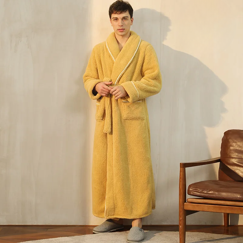 Man wearing a yellow robe standing in a room with a brown chair.