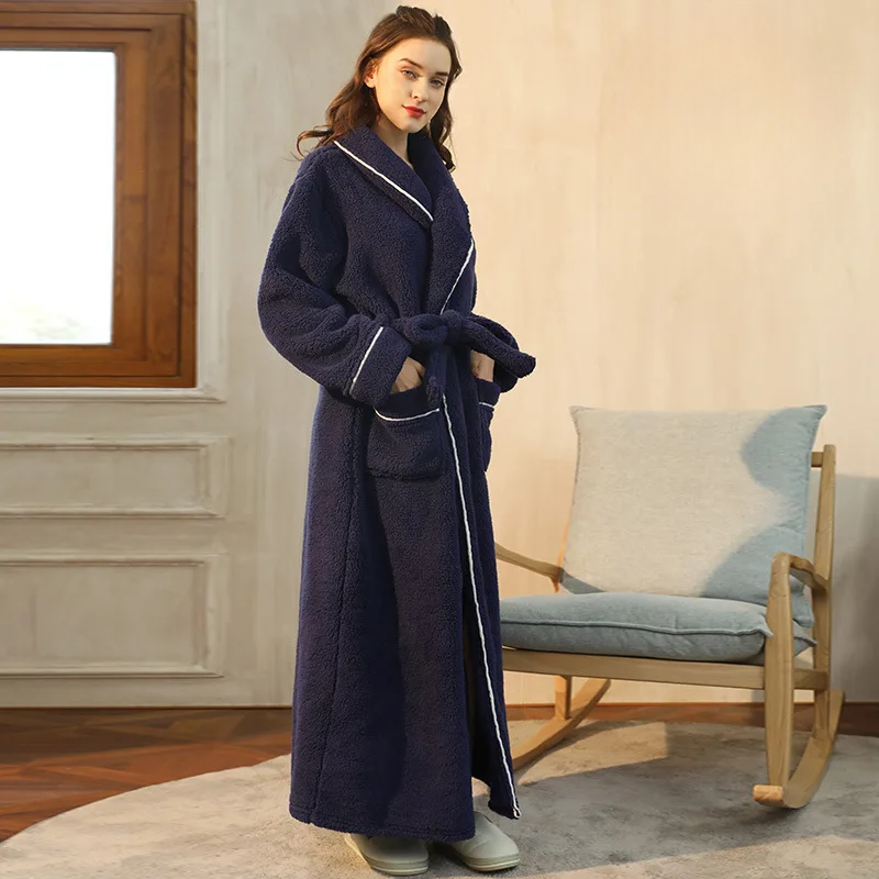 Woman wearing a long navy robe in a cozy room with a rocking chair and window.