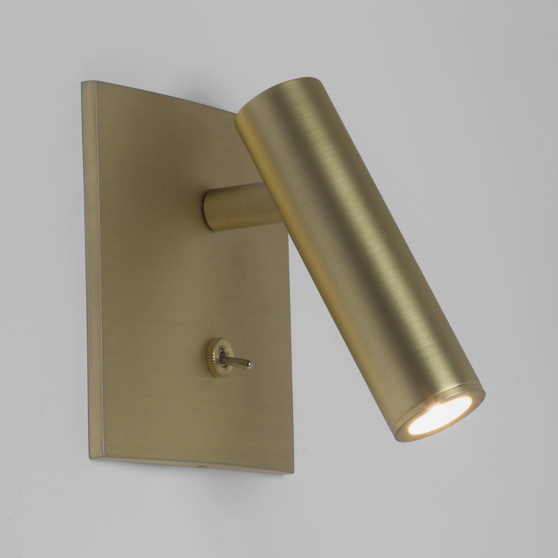 Brass wall-mounted light fixture on a gray background