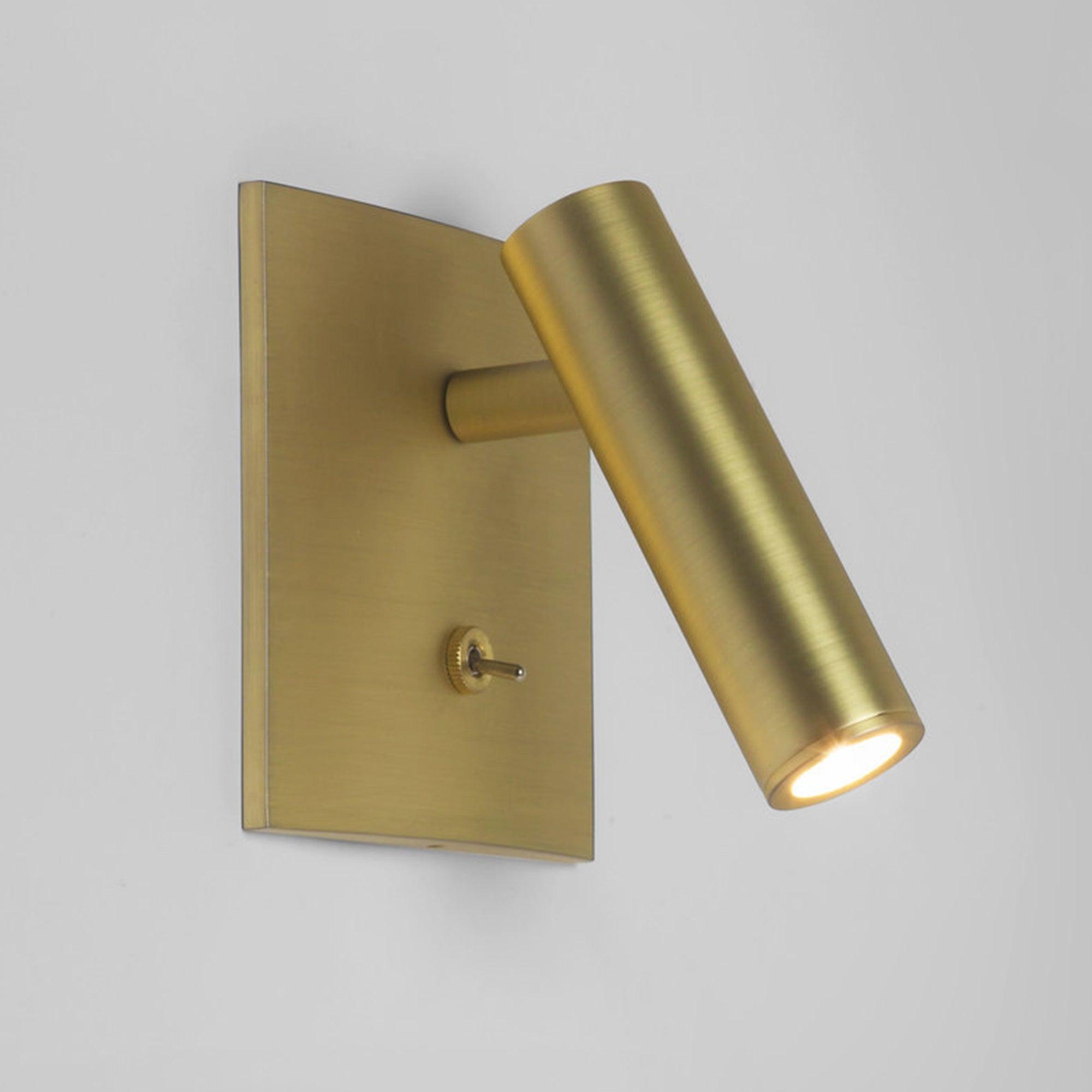 Gold wall-mounted light fixture on a gray background