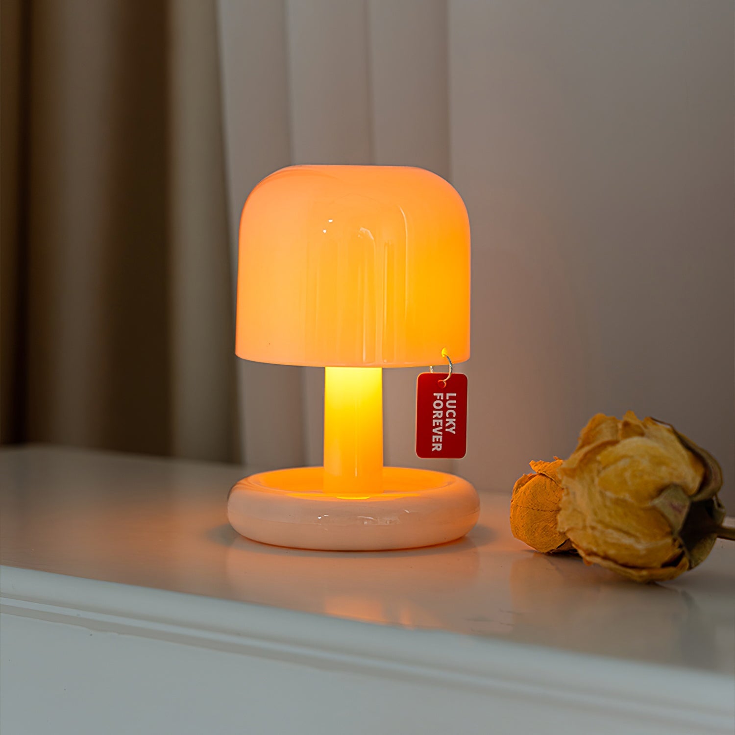 Small orange lamp with a 'Lucky Forever' tag on a surface with a blurred background