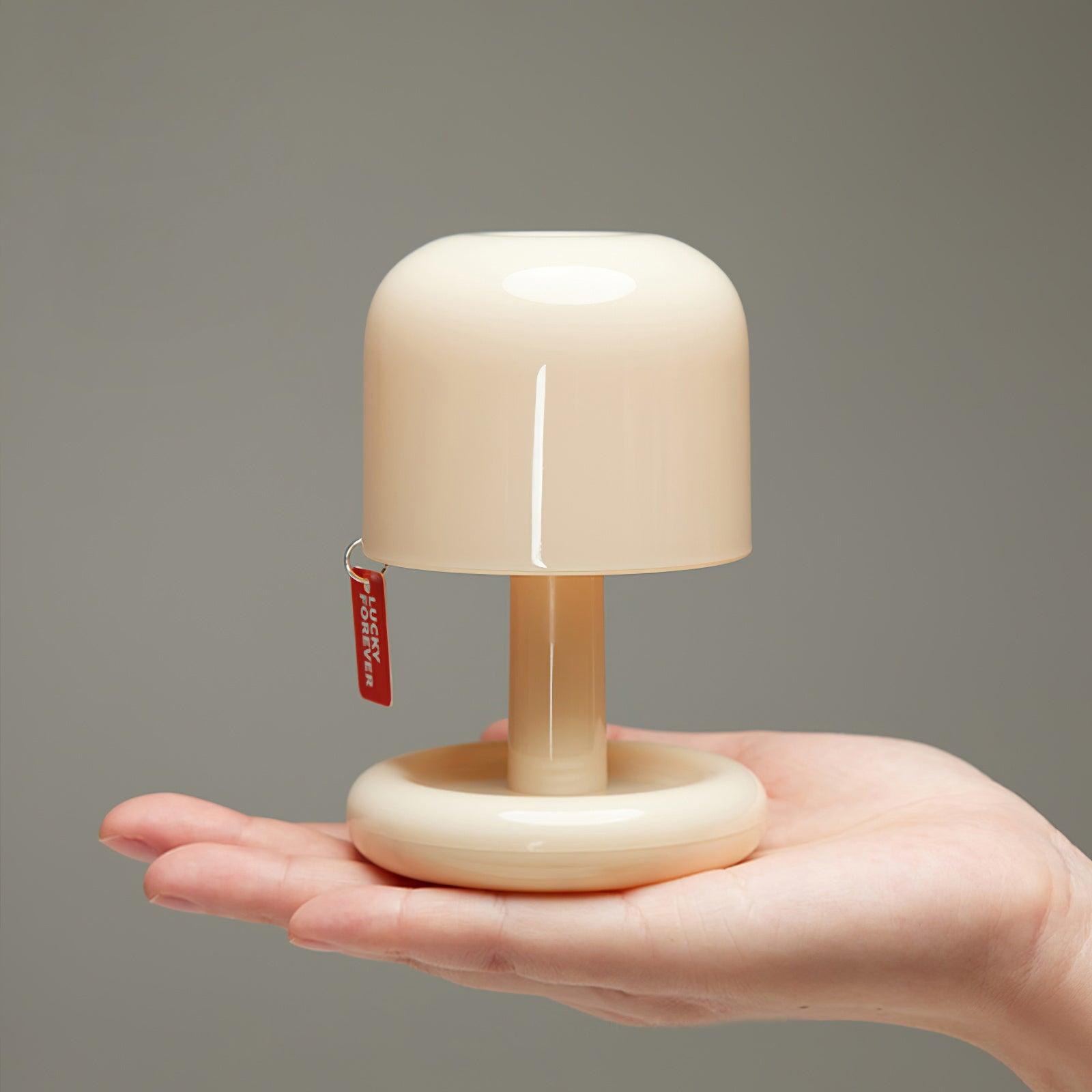 Small beige lamp held in a hand against a gray background