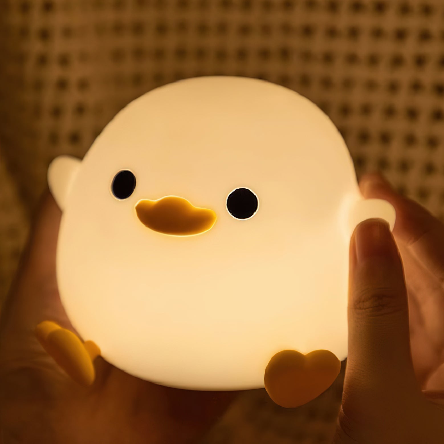 Light-up duck-shaped night light held in hands with a warm glow.