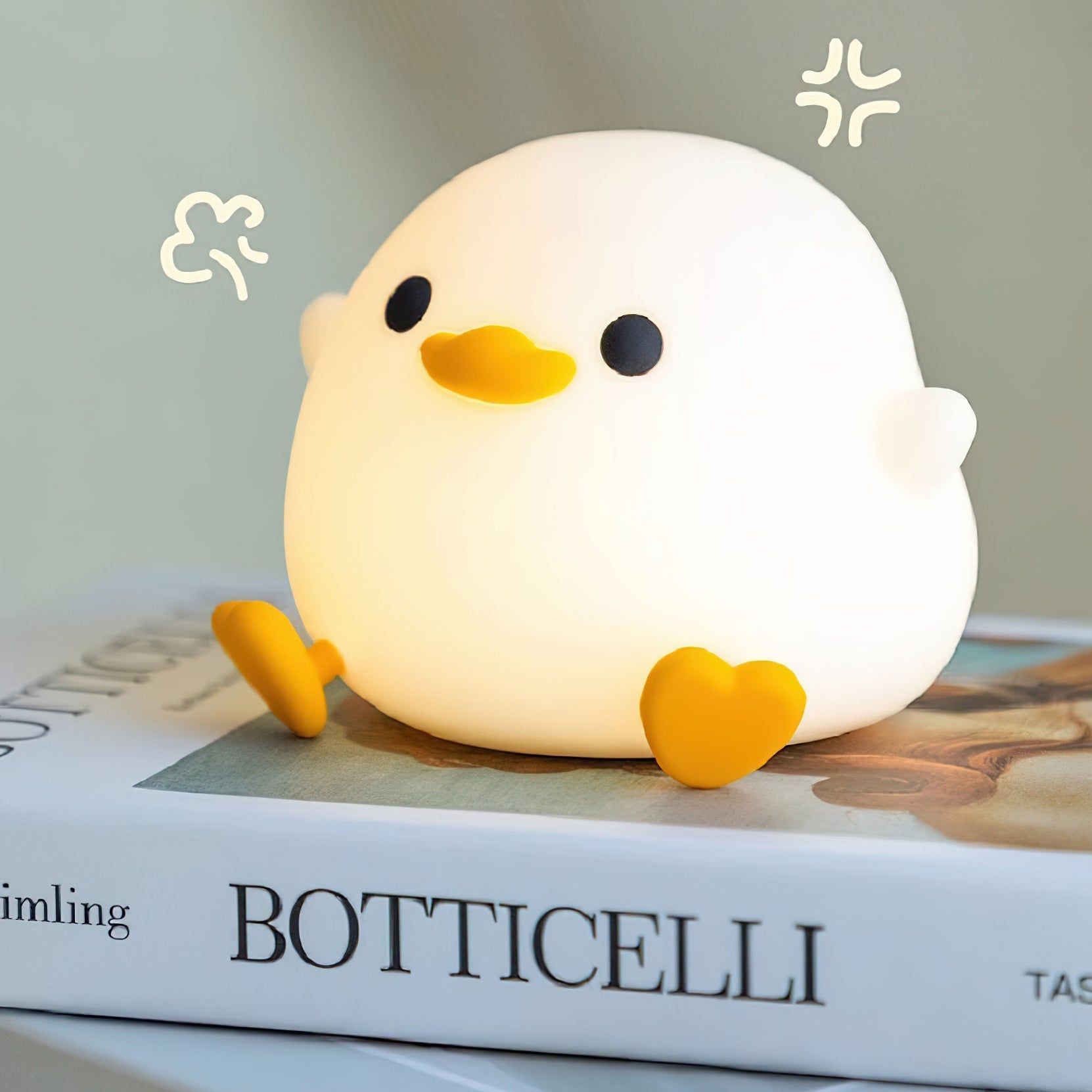 White chick-shaped night light on a book with 'Botticelli' visible