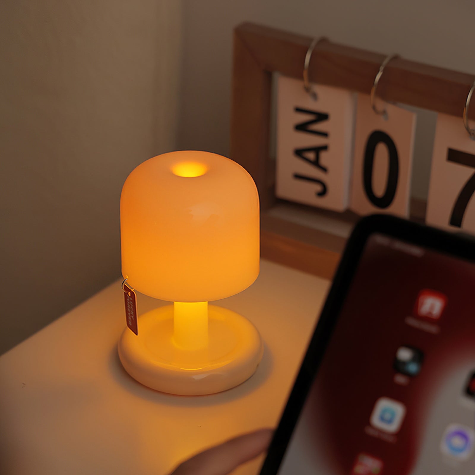 Small glowing lamp on a surface with a phone in the foreground and a calendar in the background.