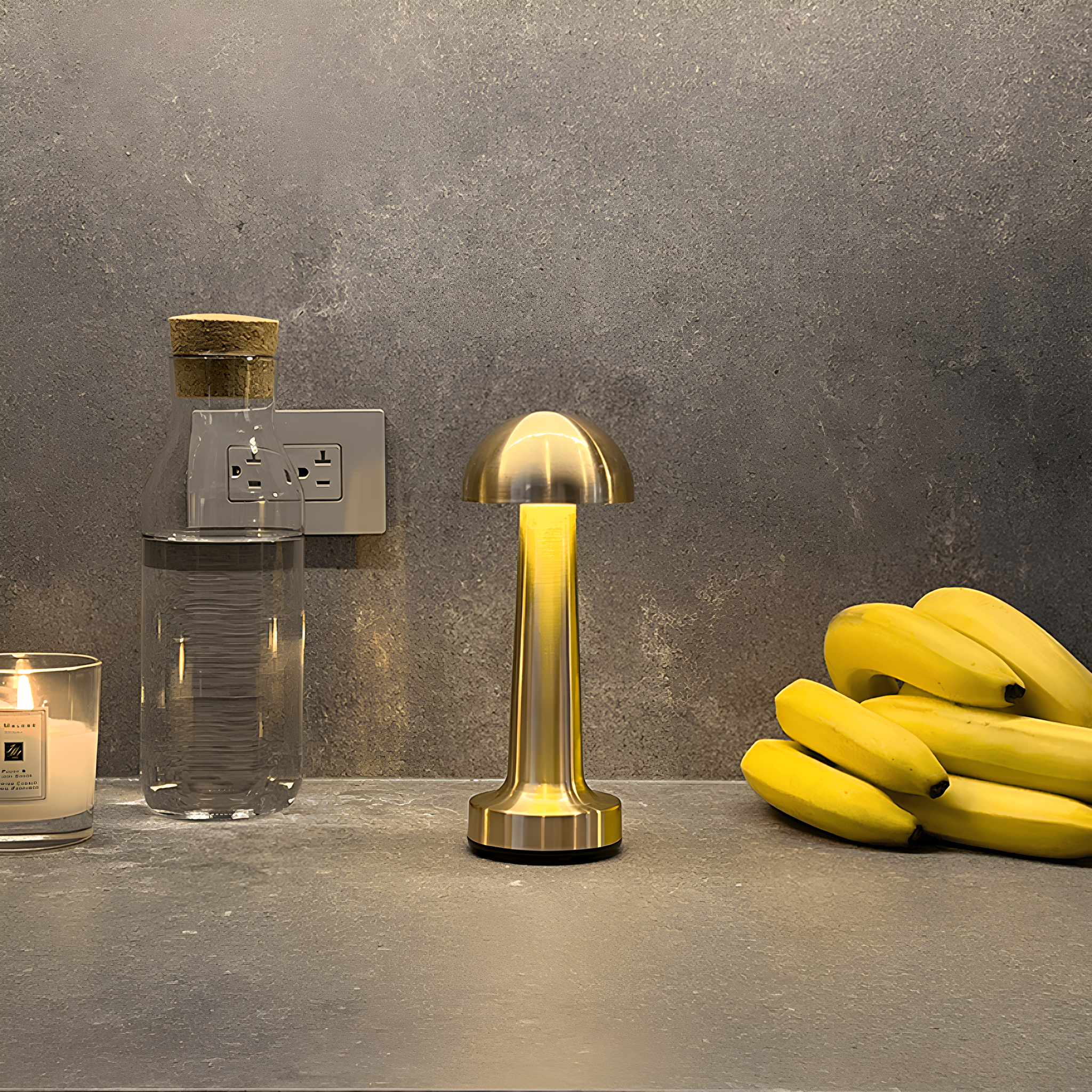 Gold lamp on a gray surface with bananas and a candle in the background