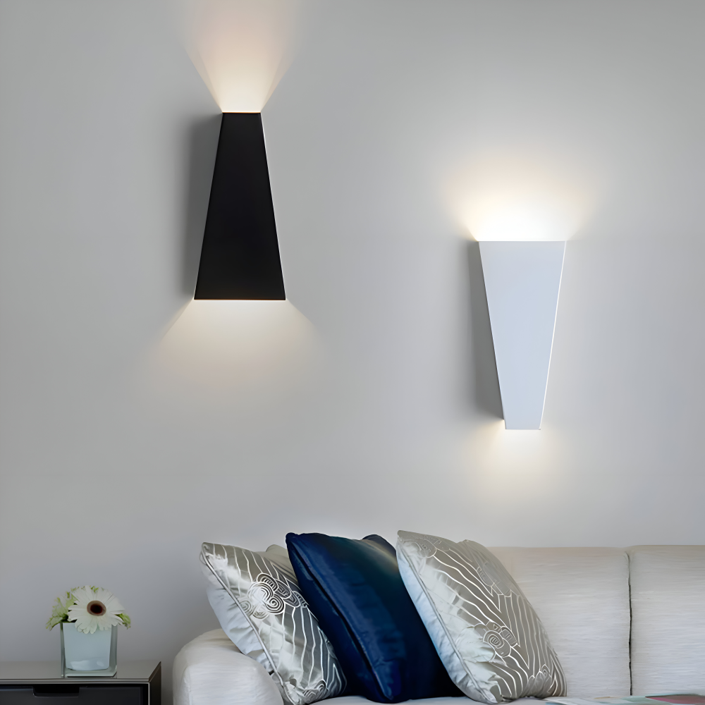 Two modern wall lights on a white wall above a sofa with decorative pillows.
