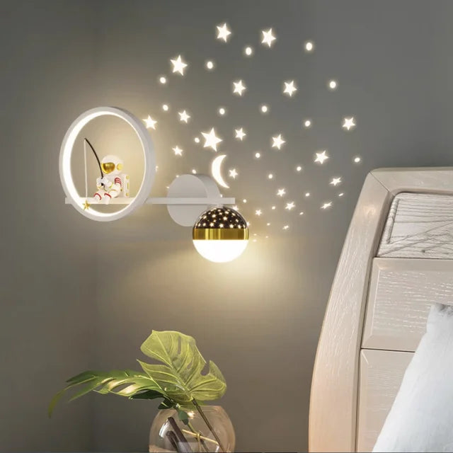 Wall lamp with decorative star stickers on a wall, next to a plant and bed.