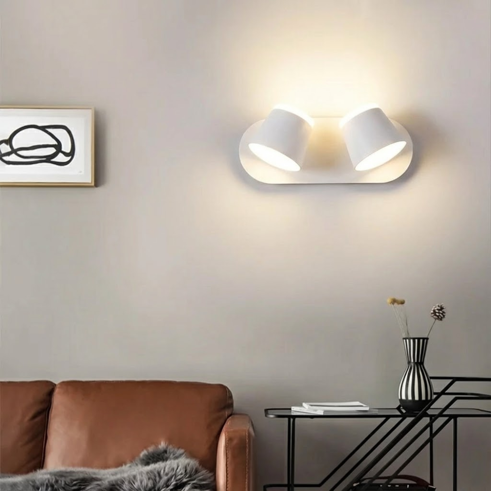 Modern wall light fixture in a living room setting with a brown sofa and decorative elements.