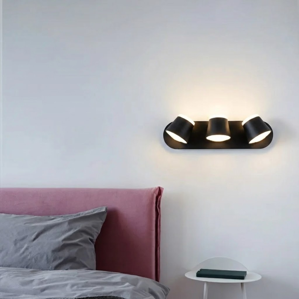 Modern wall light fixture on a white wall above a bed with pink headboard