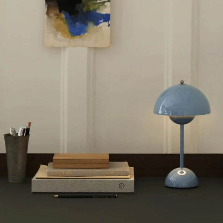 Blue lamp on a desk with books and a cup in a room setting
