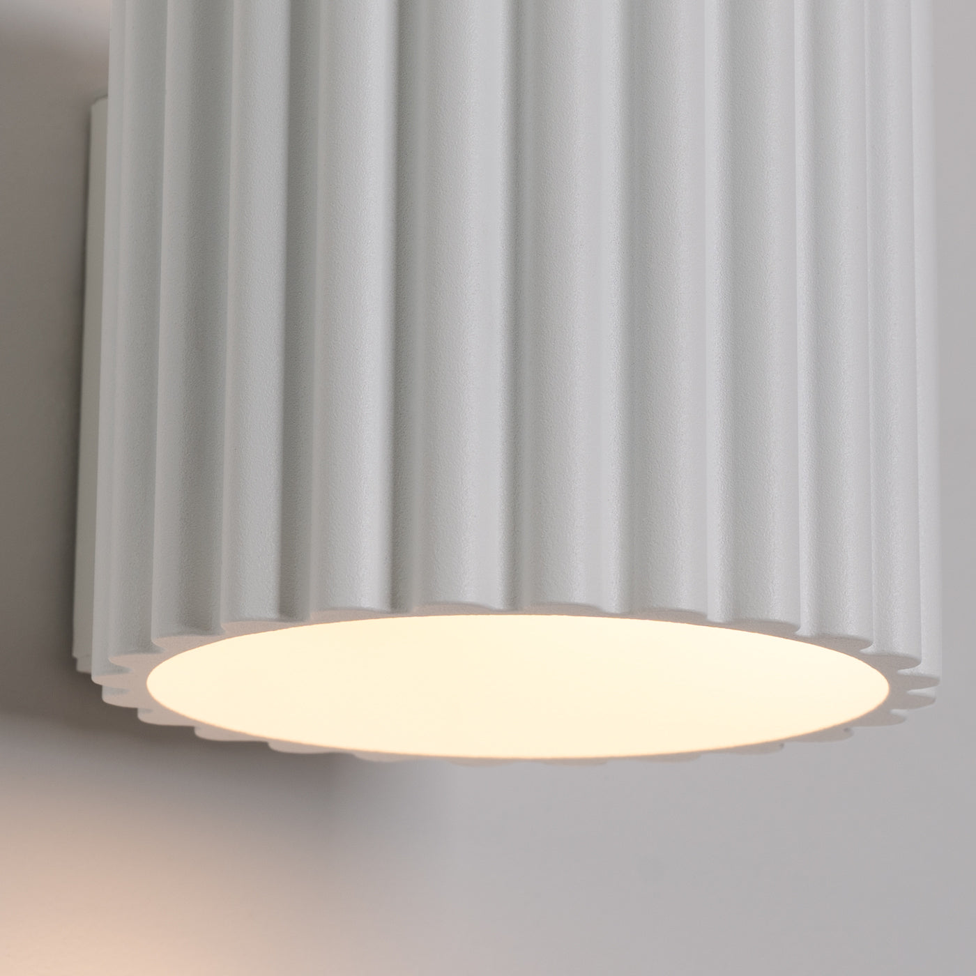 Ceiling light fixture with ribbed white cover on a neutral background