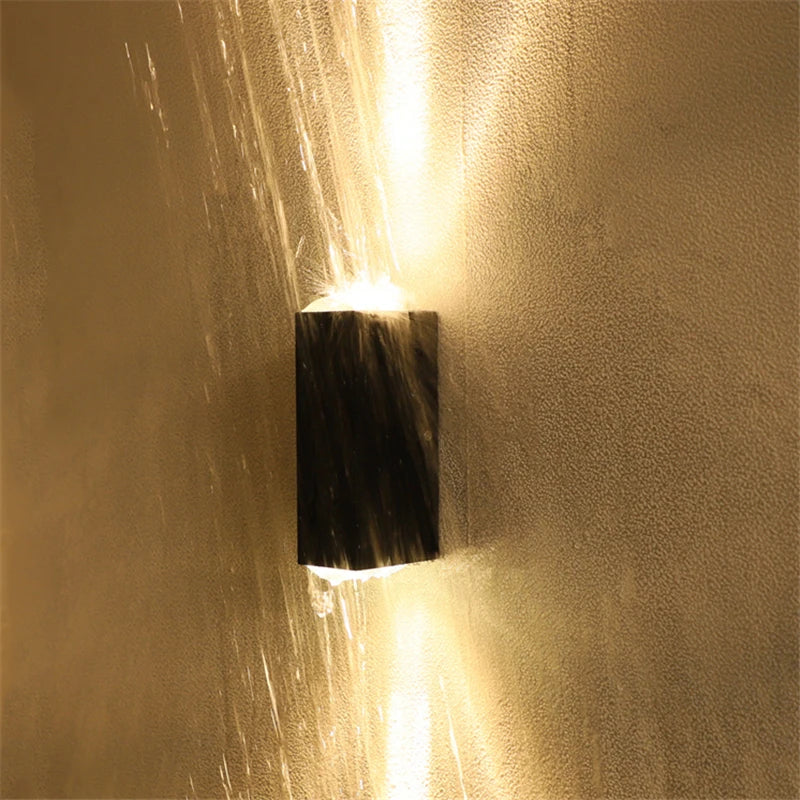 Wall-mounted light fixture casting a warm glow on a textured wall.