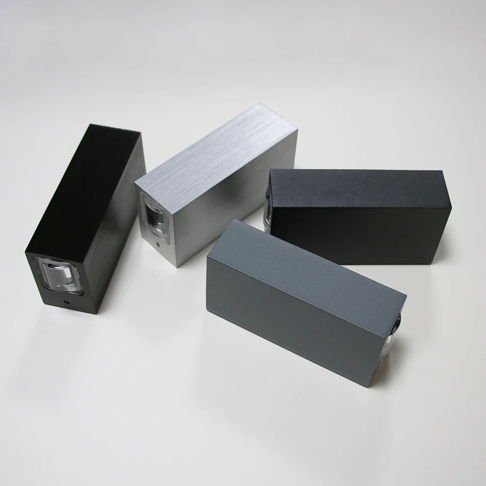 Four rectangular metal blocks in black, gray, and silver on a white background