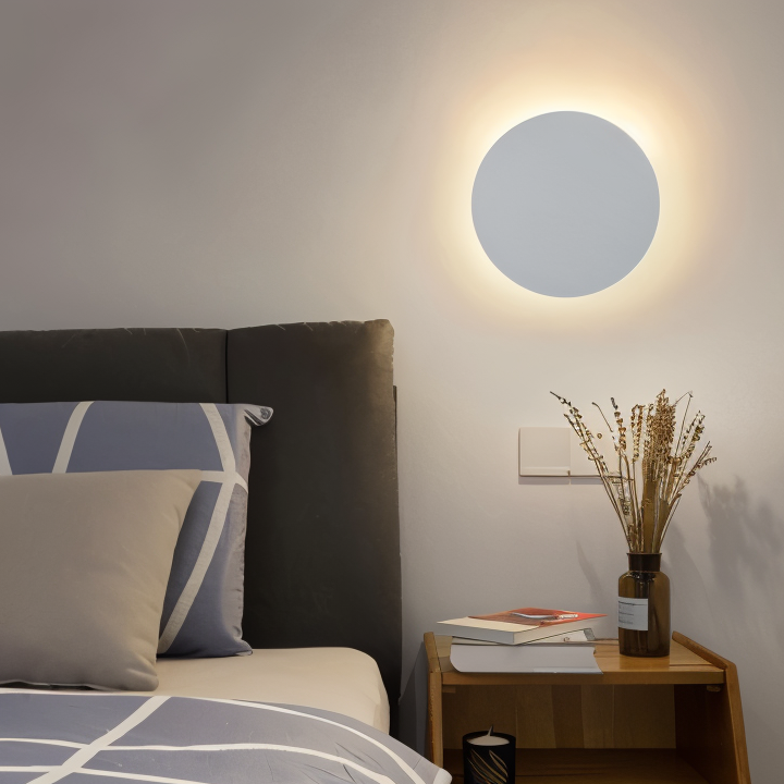 Round wall light fixture in a bedroom setting with a bed and side table.